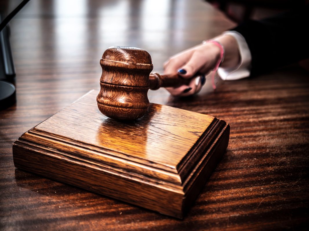 A judge lifting a gavel from a wooden block