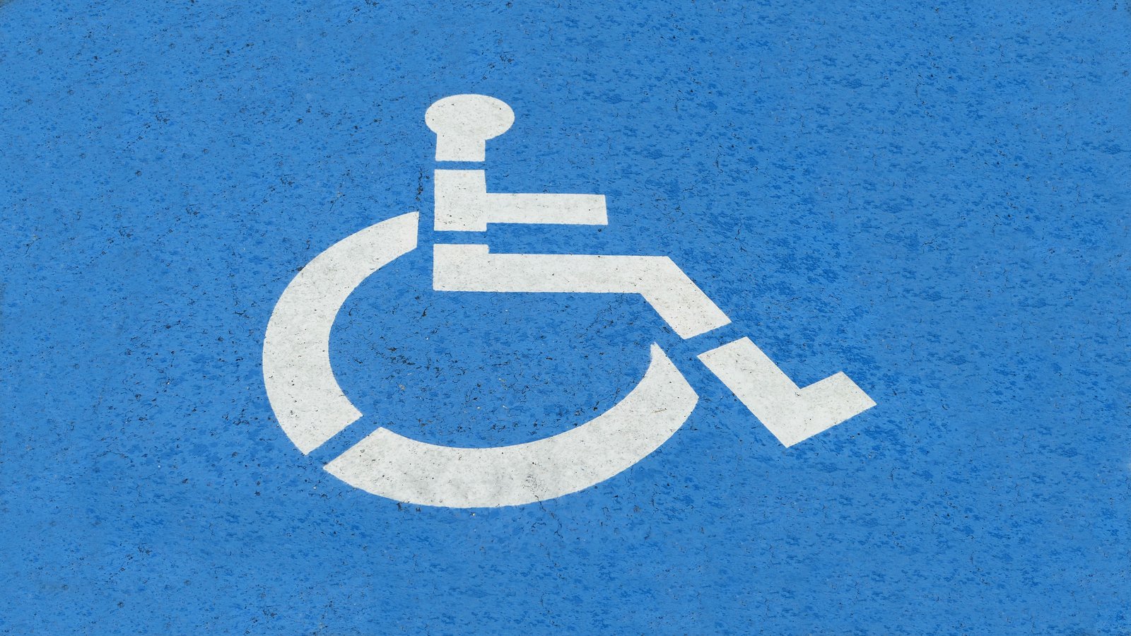 Accessibility symbol painted on blue pavement