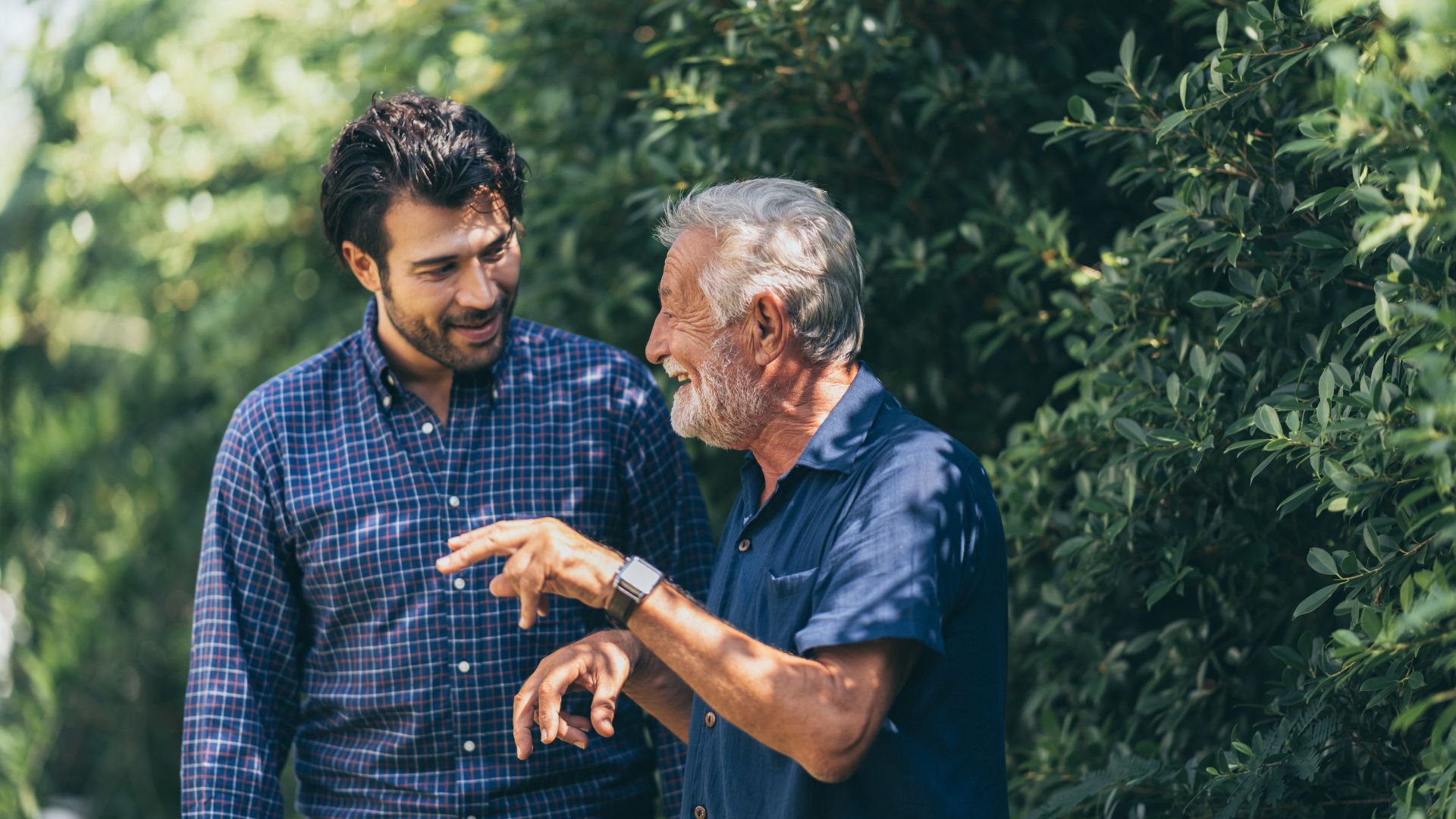 Adult son walking outdoors with his elderly father